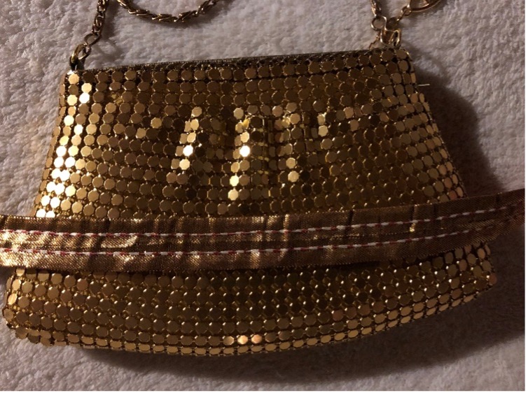 Metallic gold chainmail purse with a gold strap laid across the center